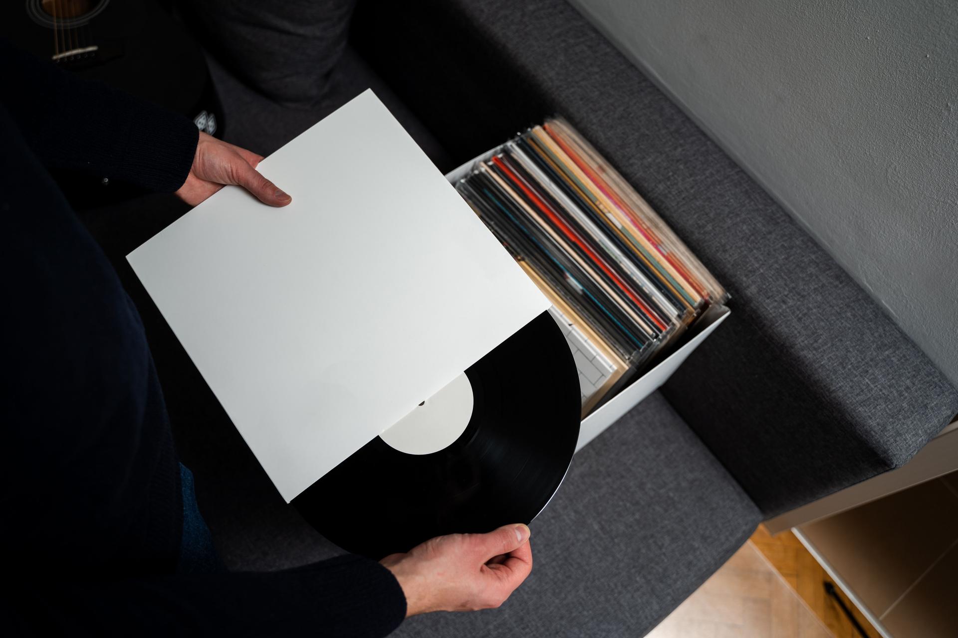 Vinyl music lover is selecting rock vinyl album from collection. Listen to music at home. Collection of vintage vinyl records at home.