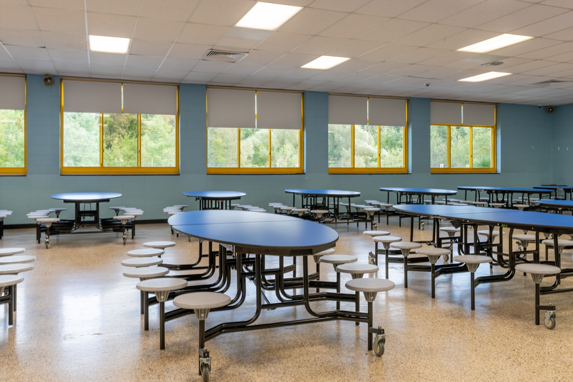 Blue folding table with attached seats in a school cafeteria.