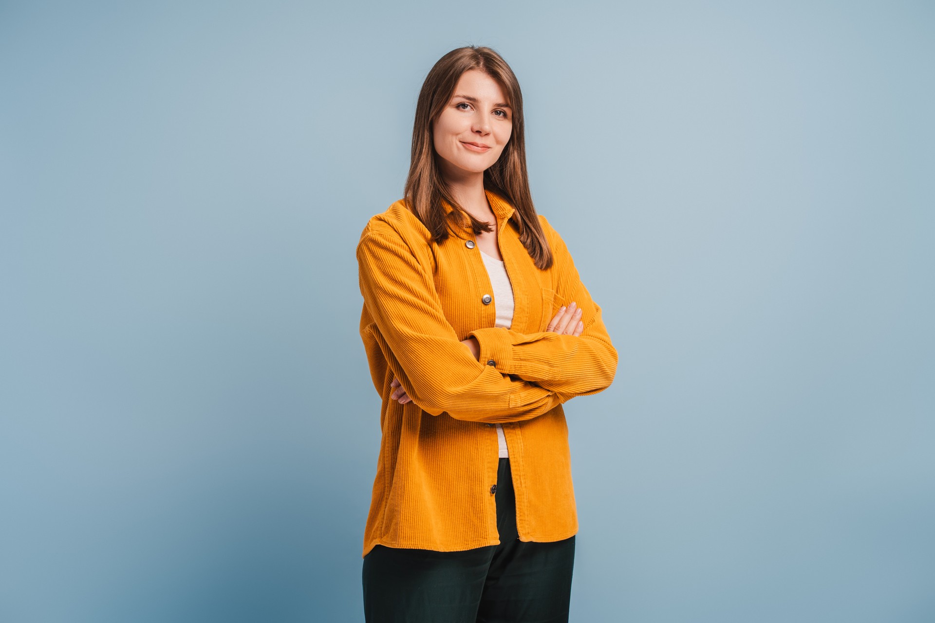 Beautiful, attractive, middle aged woman wearing casual yellow shirt with arms crossed