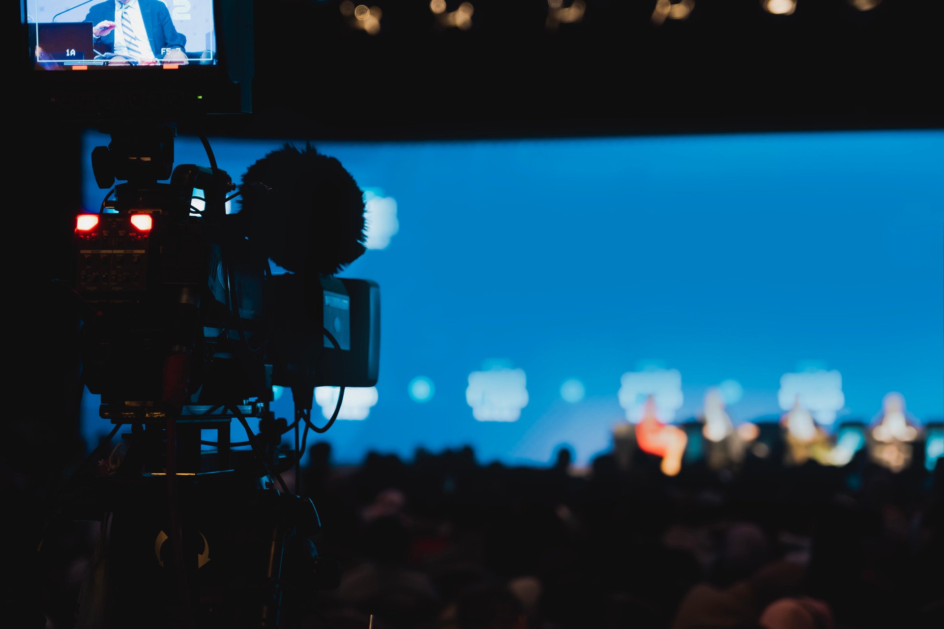 The camera connected to the live broadcast vehicle has its tally light on while participants are speaking at an international conference being broadcasted live on a news channel.