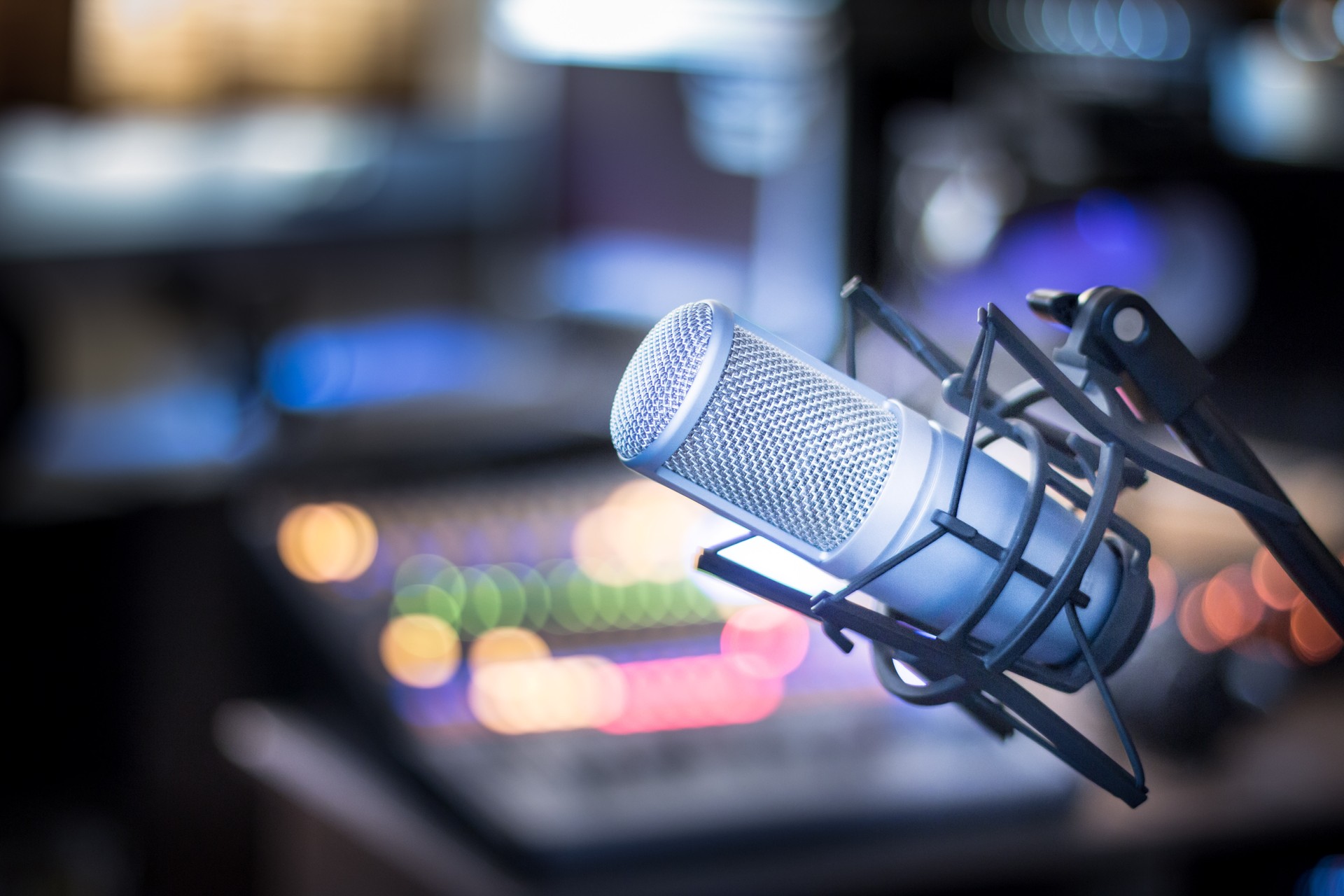 Microphone in a professional recording or radio studio, equipment in the blurry background